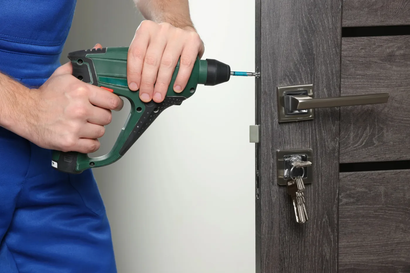 Serrurier de l'atelier vissant une serrure de sûreté sur une porte à Sèvres